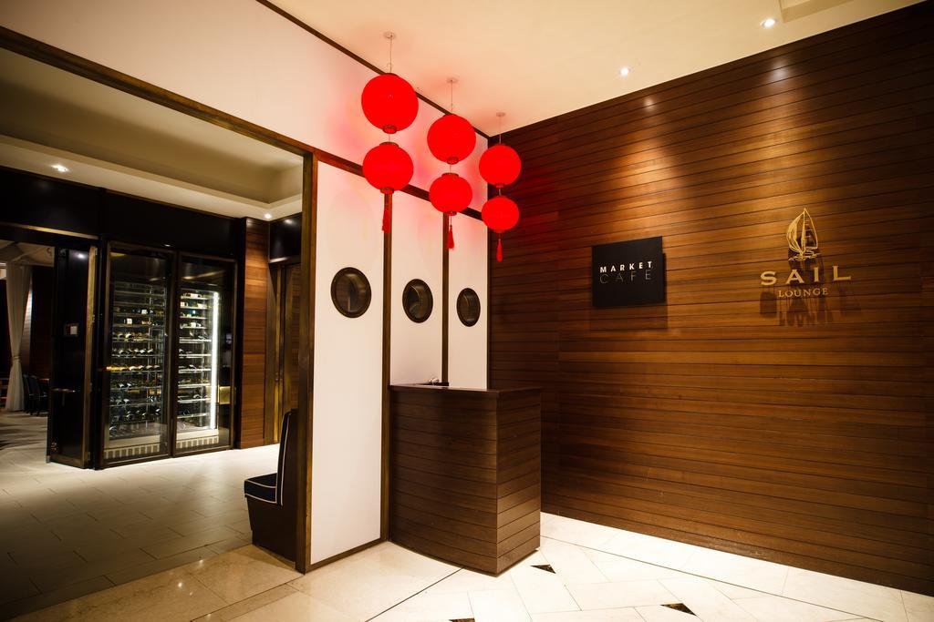 Ambassador Hotel Kaohsiung Buitenkant foto The photo shows the interior of a restaurant or establishment named "SAIL." The entrance features a wooden wall with a logo displayed prominently. There are decorative red lanterns hanging above the reception area, which has a sleek, modern design. O