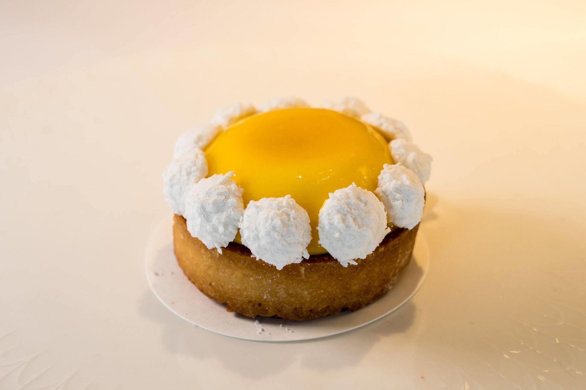Ambassador Hotel Kaohsiung Buitenkant foto The photo showcases a round dessert, likely a tart or mini cake. The base appears to be a golden-brown, crumbly crust. It is topped with a bright yellow custard or gel-like layer, which gives it a vibrant appearance. Surrounding the yellow center is 